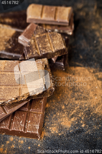 Image of Broken chocolate stacked on black background. Chocolate bar piec