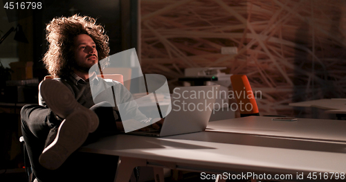 Image of businessman sitting with legs on desk at office