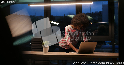 Image of black businesswoman using a laptop in night startup office