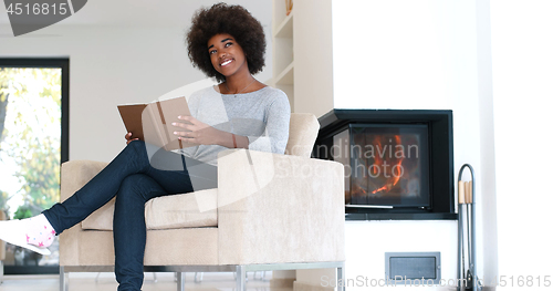 Image of black woman at home reading book