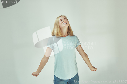 Image of The happy freckled woman standing and smiling against gray background.