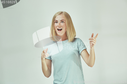 Image of The happy freckled woman standing and smiling against gray background.