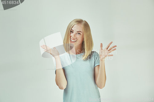 Image of The happy freckled woman standing and smiling against gray background.