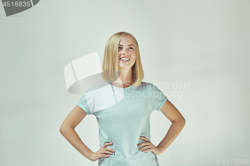 Image of The happy freckled woman standing and smiling against gray background.