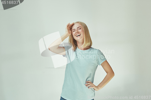 Image of The happy freckled woman standing and smiling against gray background.