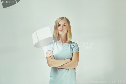 Image of The happy freckled woman standing and smiling against gray background.