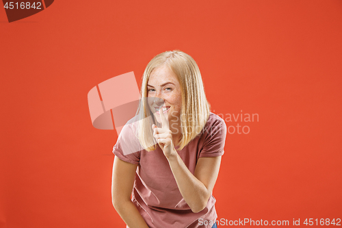 Image of The young woman whispering a secret behind her hand over red background