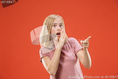 Image of The young woman whispering a secret behind her hand over red background