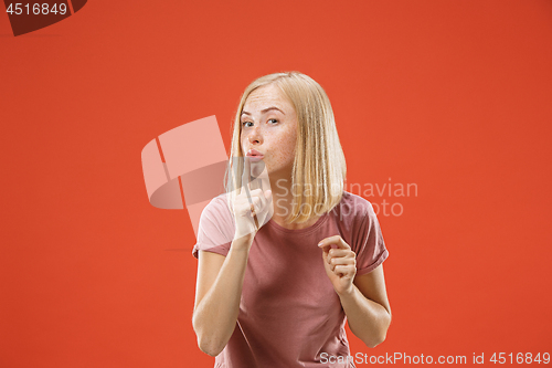 Image of The young woman whispering a secret behind her hand over red background