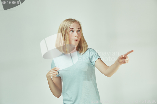 Image of The young woman whispering a secret behind her hand over gray background