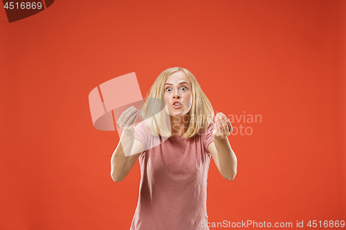 Image of Beautiful female half-length portrait isolated on red studio backgroud. The young emotional surprised woman