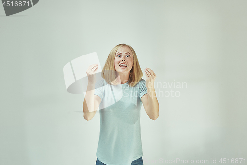 Image of Beautiful female half-length portrait isolated on gray studio backgroud. The young emotional surprised woman