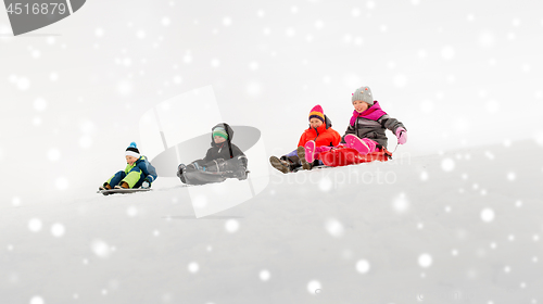 Image of kids sliding on sleds down snow hill in winter