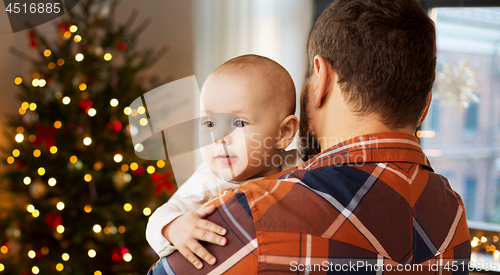 Image of close up of father holding baby son on christmas