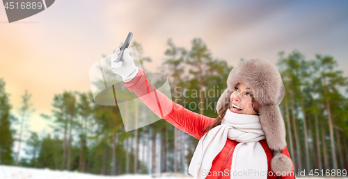 Image of happy woman taking selfie over winter forest