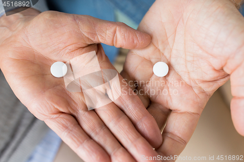 Image of close up of senior couple hands with pills