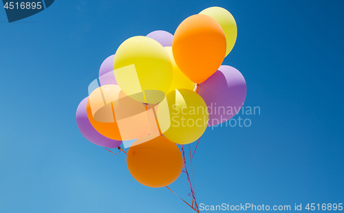 Image of close up of colorful helium balloons in blue sky