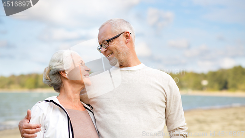 Image of happy senior couple hugging over beach background