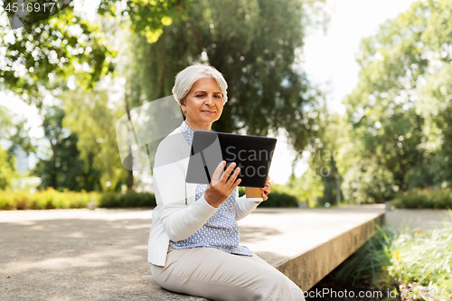 Image of old woman with tablet pc and coffee at summer park