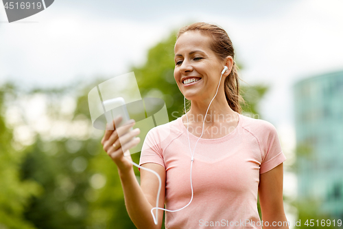 Image of woman listening to music on smartphone at park