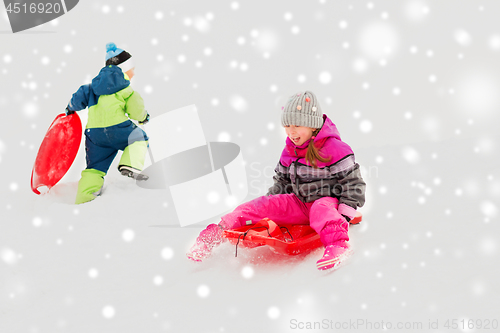 Image of happy kids sliding on sleds down hill in winter