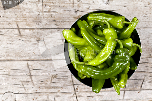 Image of Fresh green raw peppers in metal bowl on rustic wooden table bac