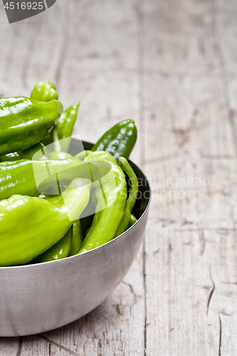 Image of Fresh green raw peppers in metal bowl on rustic wooden table bac