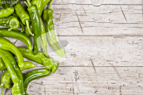 Image of Fresh green raw peppers on rustic wooden table background. 