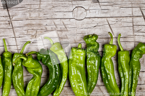 Image of Fresh green raw peppers on rustic wooden table background. 