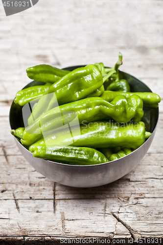 Image of Fresh green raw peppers in metal bowl on rustic wooden table bac