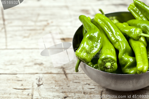 Image of Fresh green raw peppers in metal bowl on rustic wooden table bac