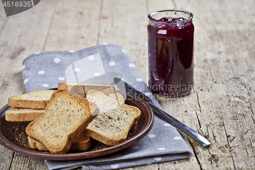 Image of Toasted cereal bread slices on grey plate and jar with homemade 