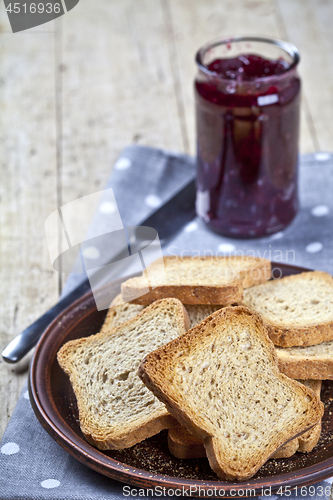 Image of Toasted cereal bread slices on grey plate and jar with homemade 