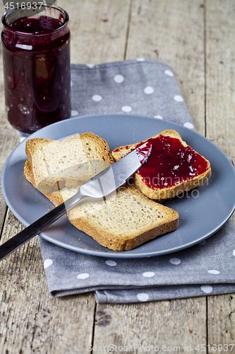 Image of Fresh toasted cereal bread slices on grey plate and jar with hom