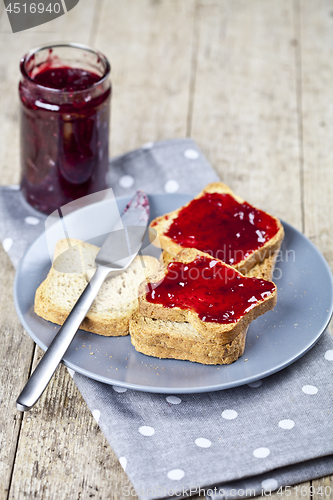 Image of Toasted cereal bread slices on grey plate and jar with homemade 