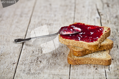 Image of Toasted cereal bread slices with homemade cherry jam and spoon c