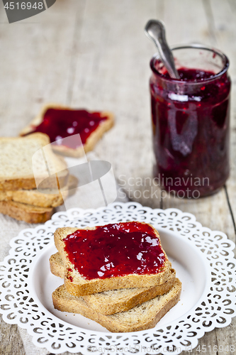 Image of Toasted cereal bread slices on white plate and jar with homemade