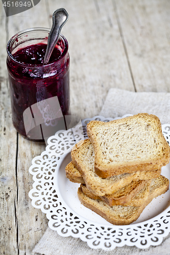 Image of Homemade cherry jam in glassjar and fresh toasted cereal bread s