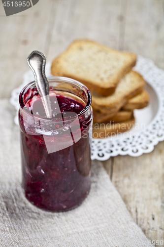 Image of Jar with homemade cherry jam and fresh toasted cereal bread slic