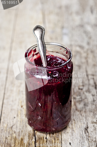 Image of Fresh cherry homemade jam in jar on rustic wooden background.