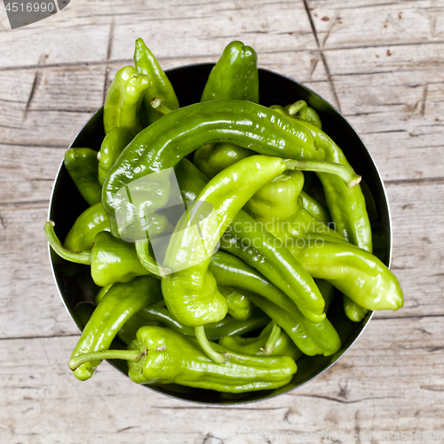 Image of Fresh green raw peppers in metal bowl on rustic wooden table bac