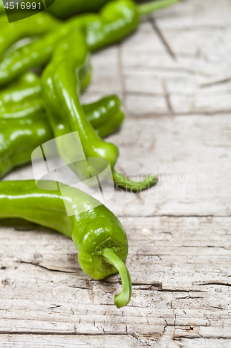 Image of Fresh green raw peppers on rustic wooden table background. 