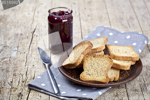 Image of Toasted cereal bread slices on grey plate and jar with homemade 