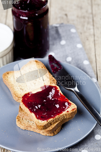 Image of Fresh toasted cereal bread slices on grey plate and jar with hom