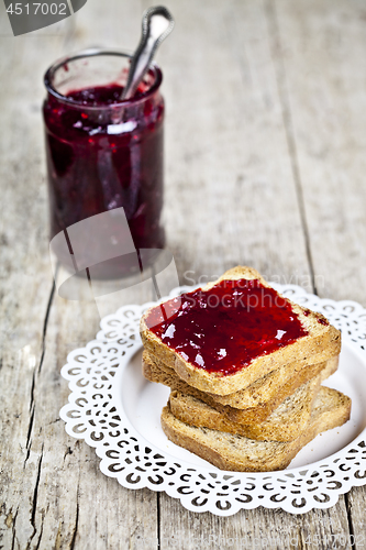 Image of Toasted cereal bread slices on white plate and jar with homemade