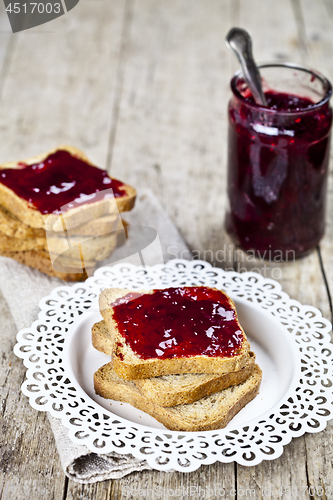 Image of Toasted cereal bread slices on white plate and jar with homemade