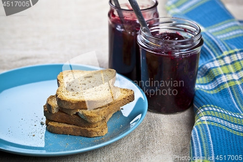 Image of Cereal bread slices on blue ceramic plate and homemade cherry an