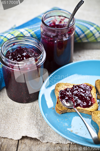 Image of Fresh cereal bread slices on blue ceramic plate, homemade cherry