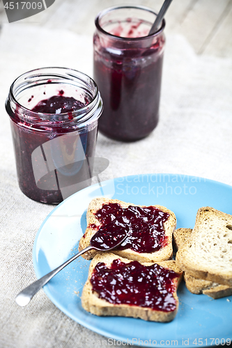 Image of Fresh cereal bread slices on blue ceramic plate, homemade cherry