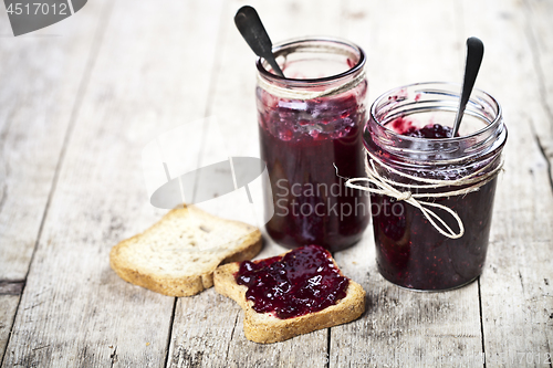 Image of Toasted cereal bread slices and jars with homemade wild berries 